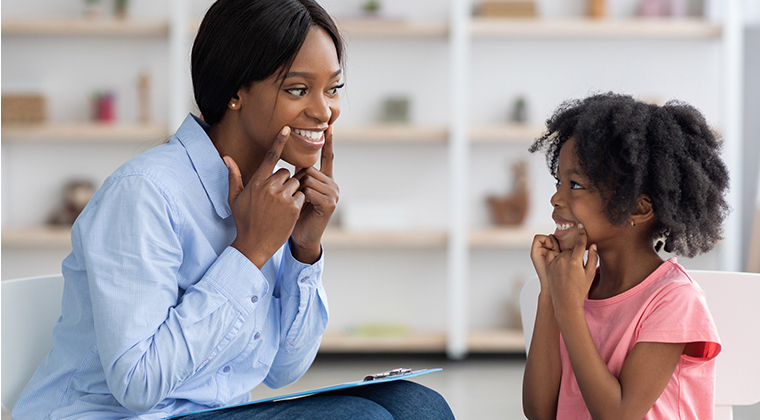 Speech therapist working with little girl at clinic